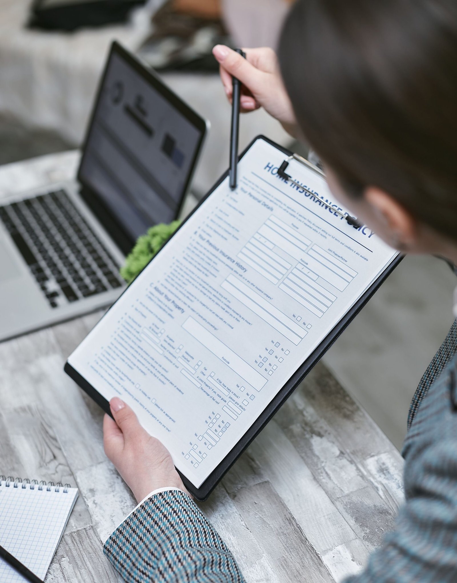 Adult reviewing an insurance policy document beside a laptop.