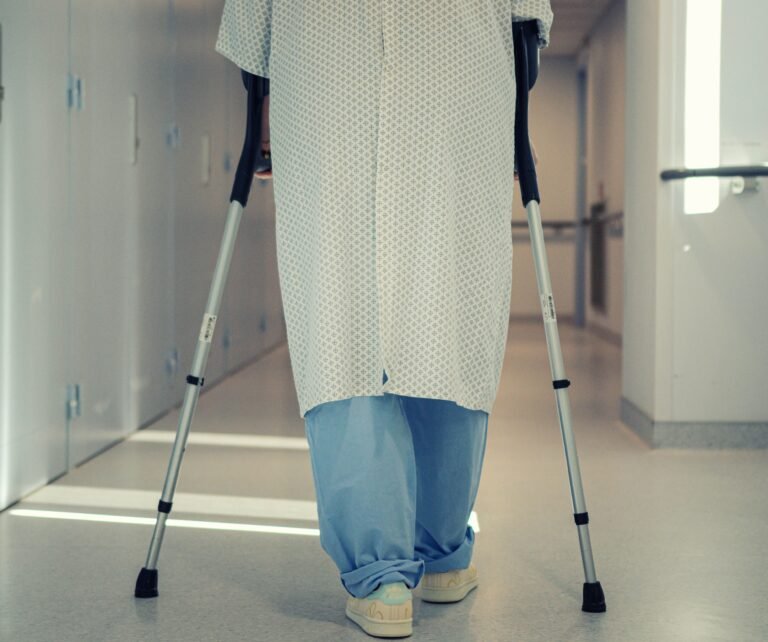 Senior patient walking with crutches in a hospital corridor during recovery