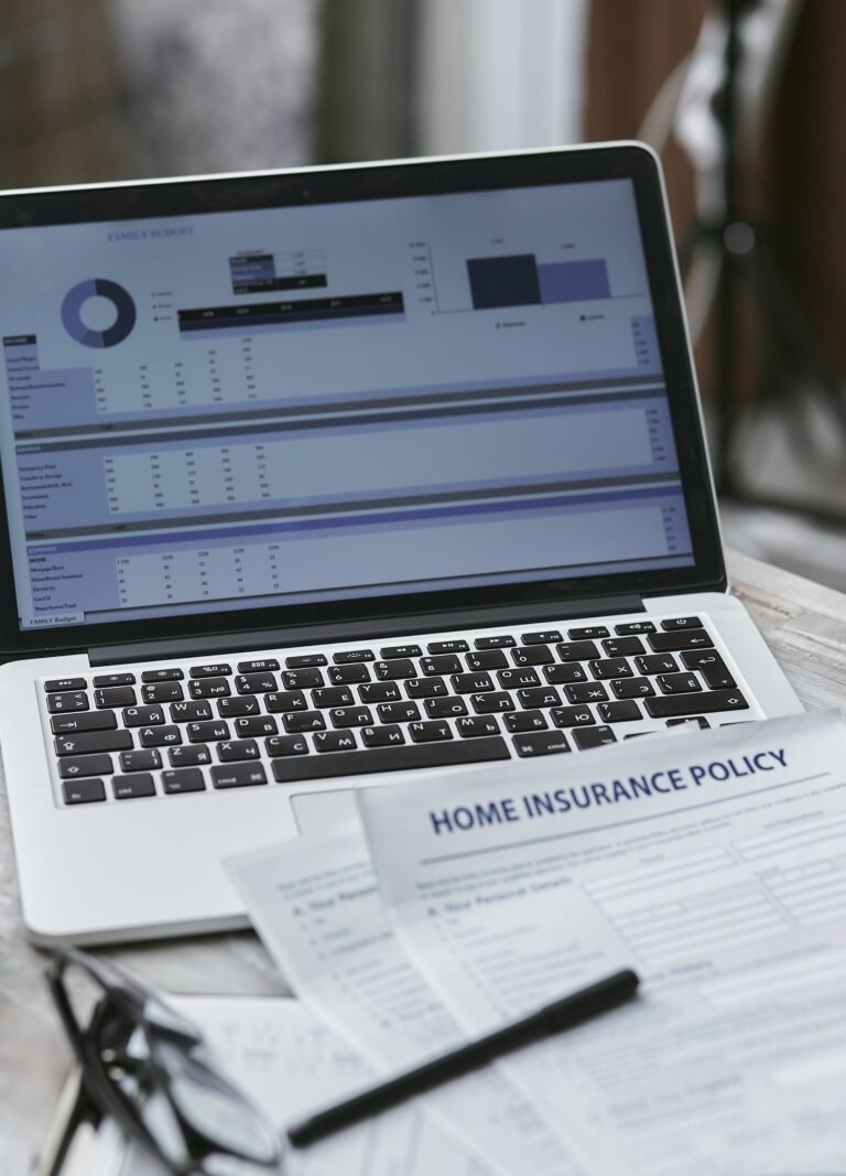 Insurance policy documents and a laptop arranged on a desk.