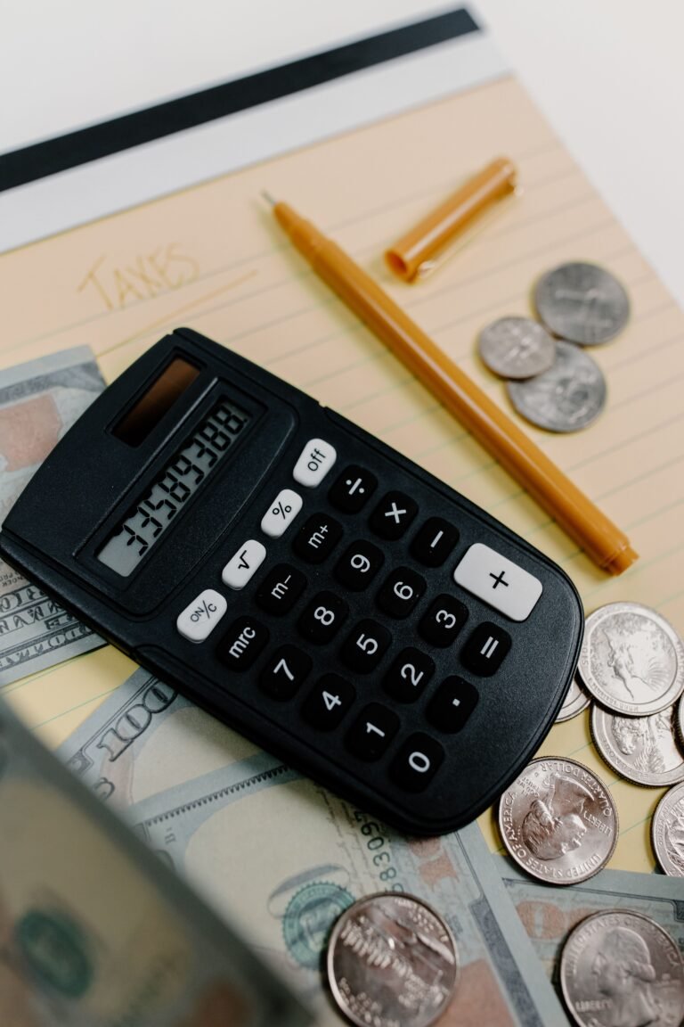 Calculator, cash, coins, notepad, and pen arranged for budgeting.