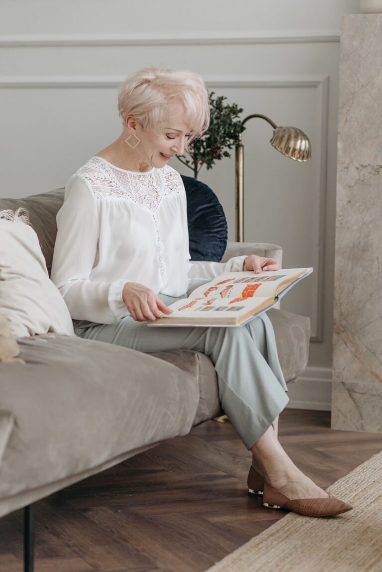 Older woman reading a magazine quietly on a sofa.