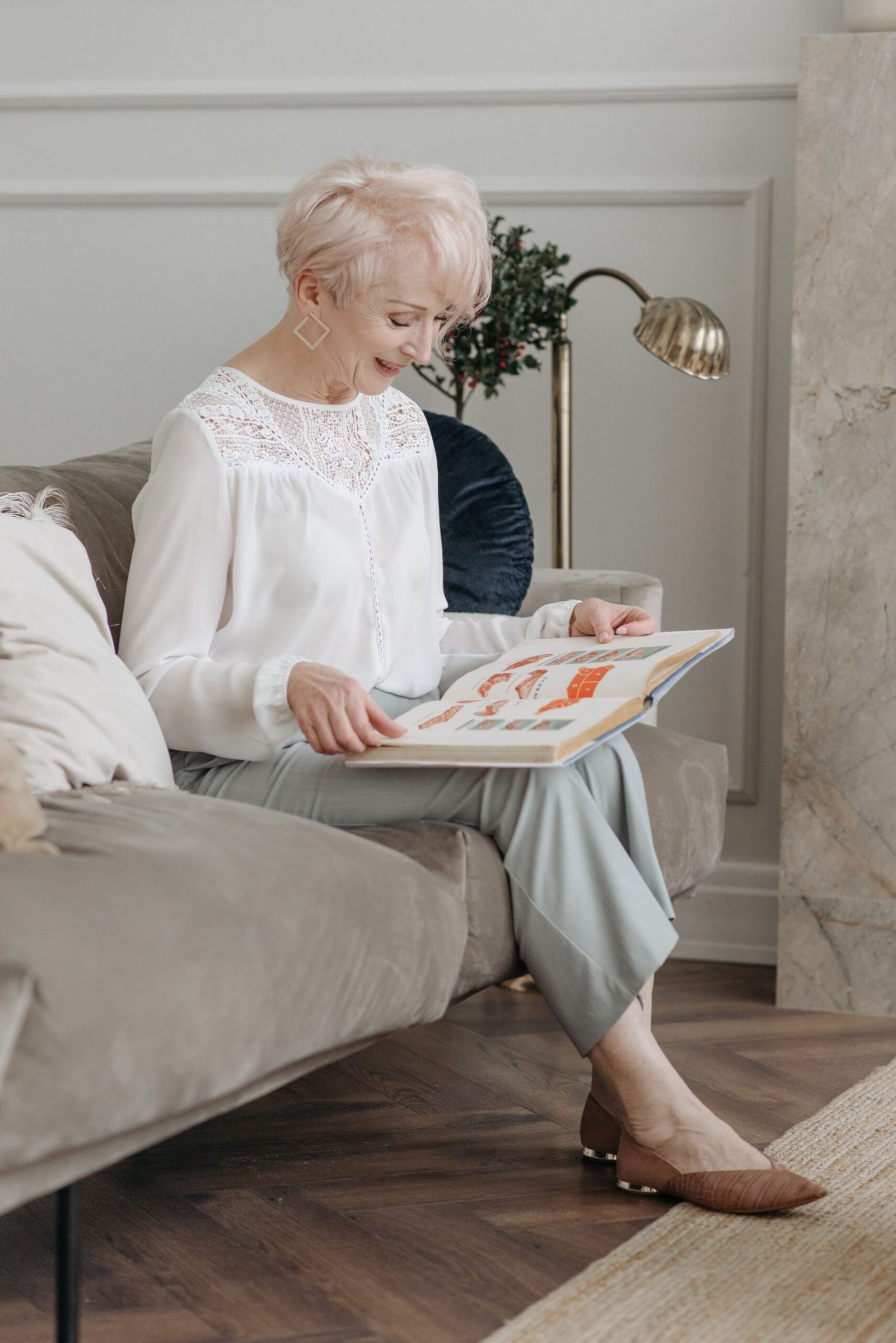 Older woman reading a magazine quietly on a sofa.
