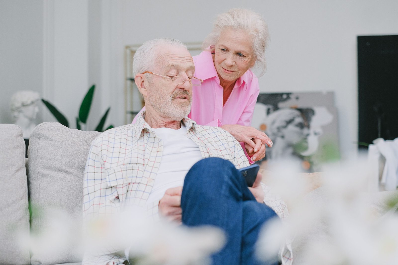 Older couple using a smartphone while talking together indoors.
