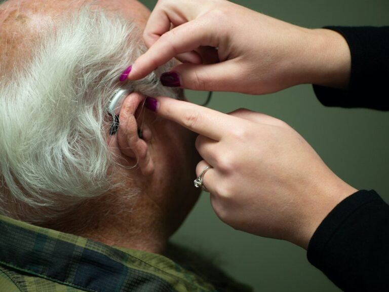 Older adult receiving a hearing check and hearing-aid support