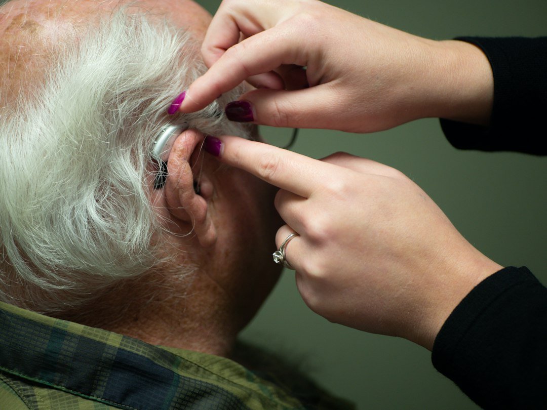 Older adult receiving a hearing check and hearing-aid support