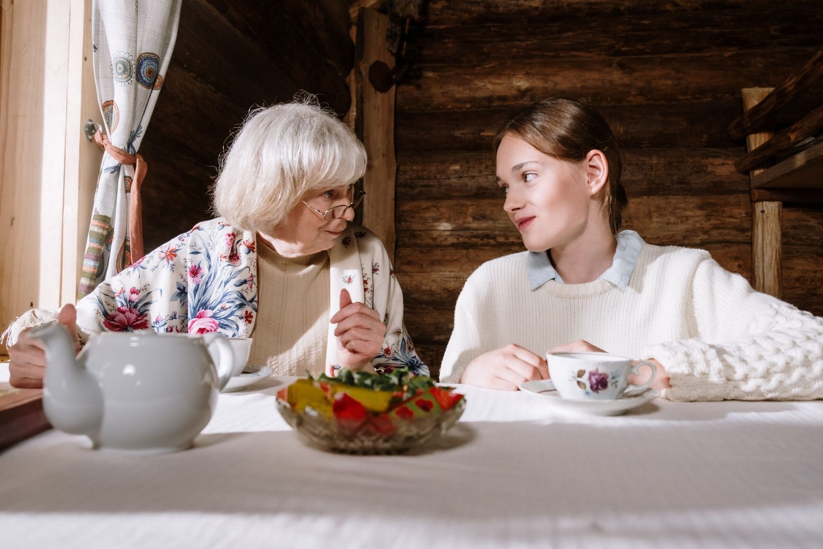 Older adult and teenager sharing tea and conversation at home.