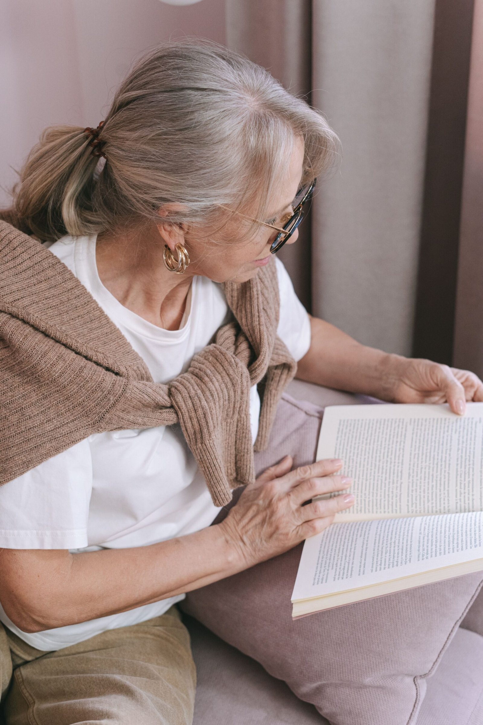 Older woman reading a book in a comfortable home setting.