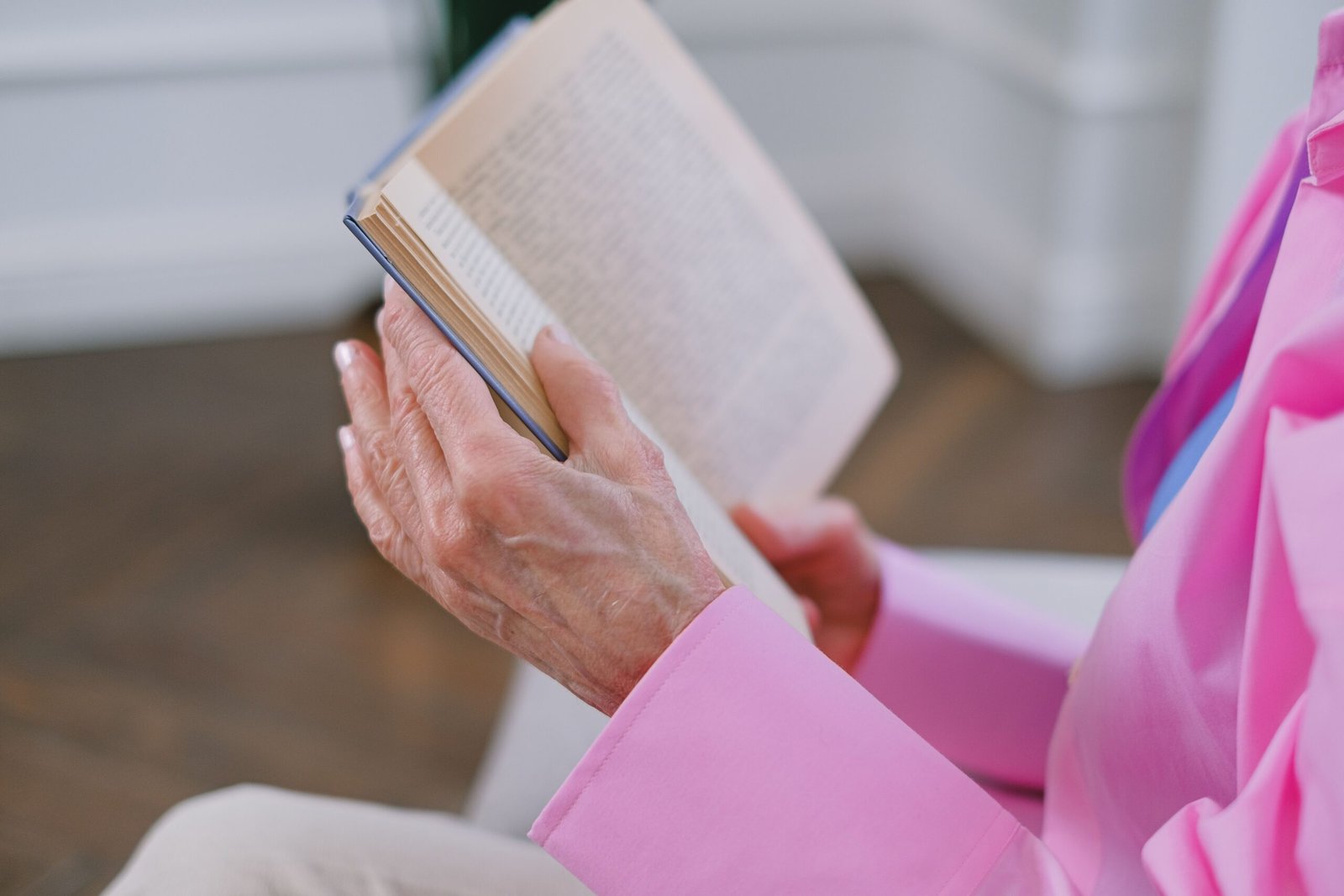Older person reading a book quietly indoors.