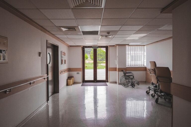 Empty wheelchair positioned near glass doors inside a healthcare building.