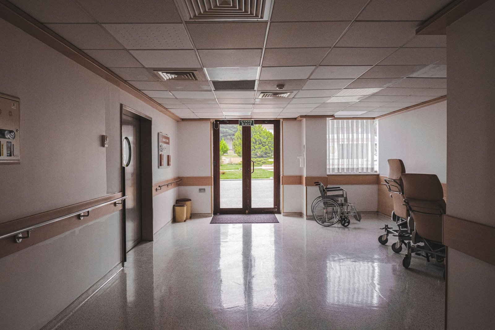 Empty wheelchair positioned near glass doors inside a healthcare building.