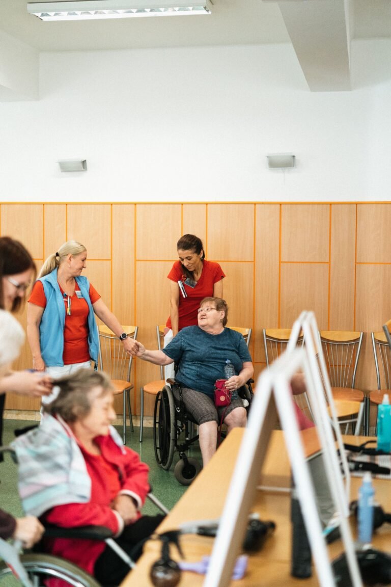 Care staff interacting with older adults in a care-facility room.