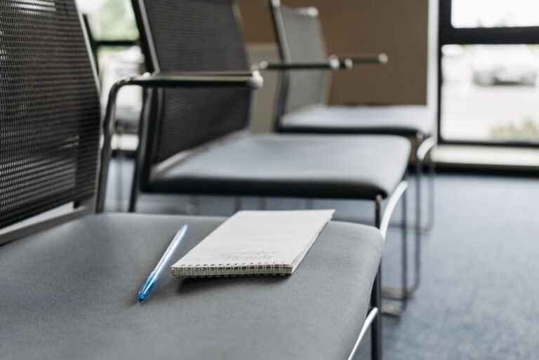 Blank notebook and pen resting on an empty chair in a quiet meeting space