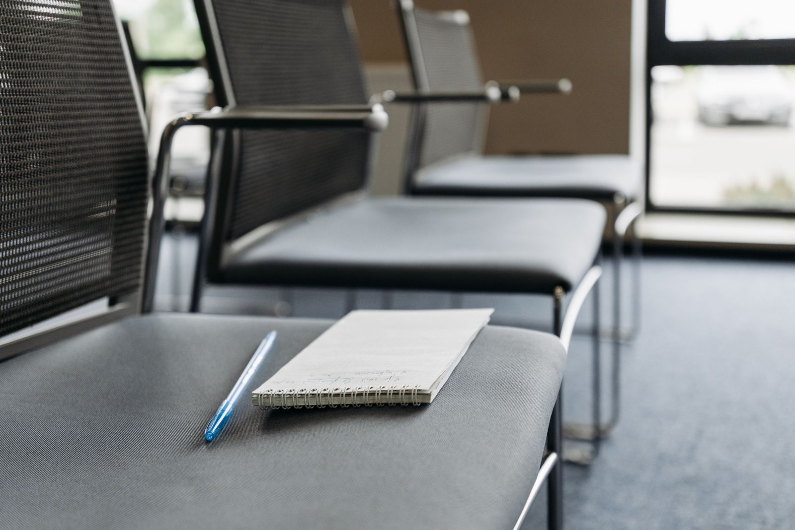 Blank notebook and pen resting on an empty chair in a quiet meeting space