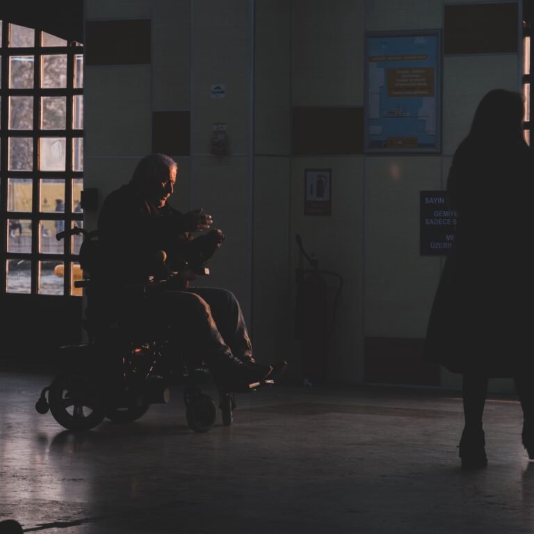 Wheelchair user silhouetted in a healthcare corridor.