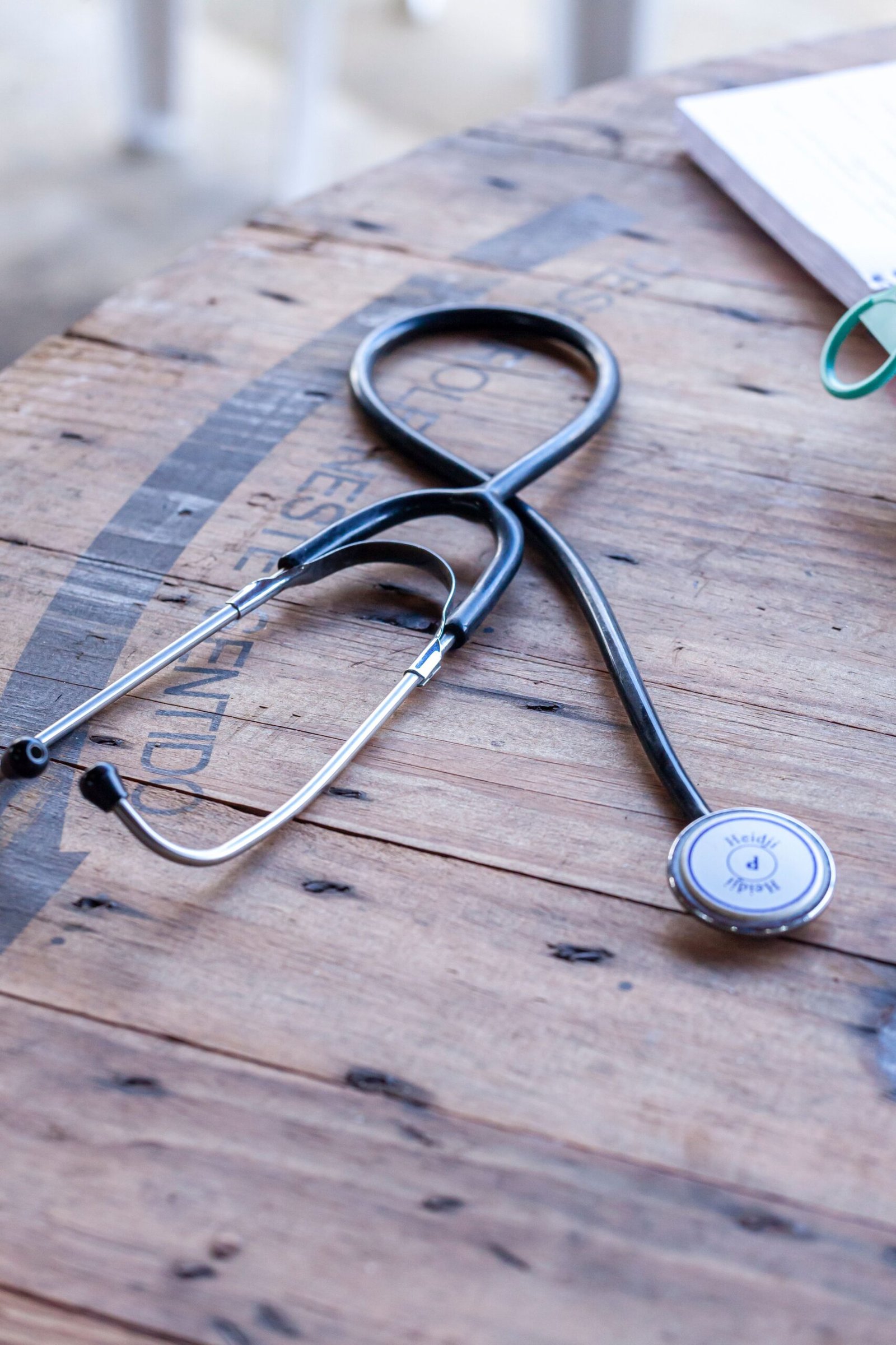 Stethoscope resting on a wooden table beside papers.