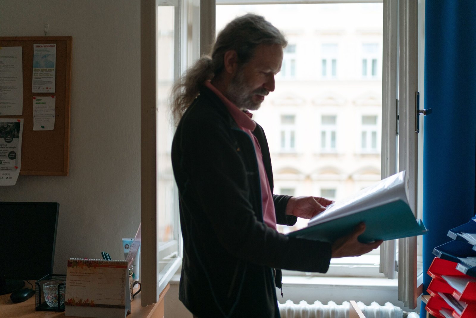 Older man reviewing assessment documents beside a window