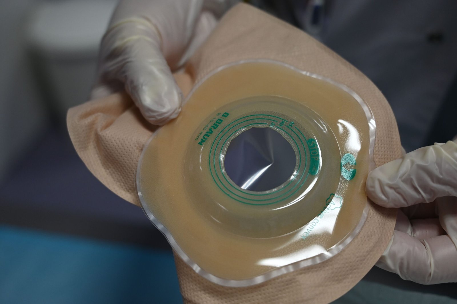 Healthcare professional holding an ostomy pouch while wearing gloves