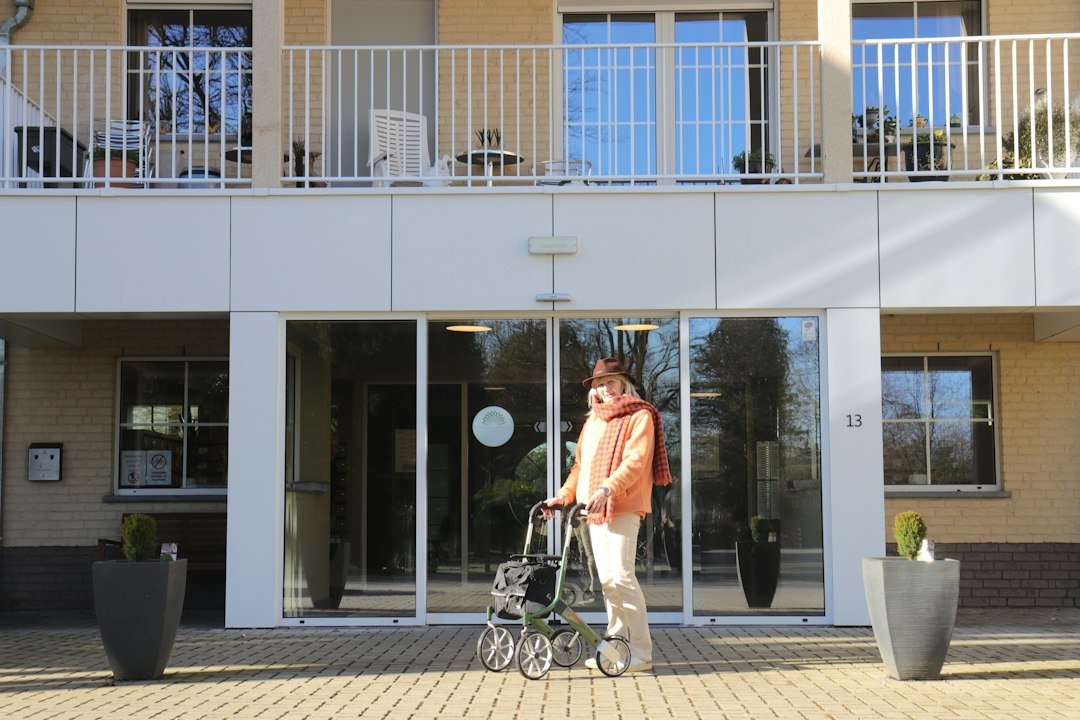 Older adult standing with a walker near a senior living building