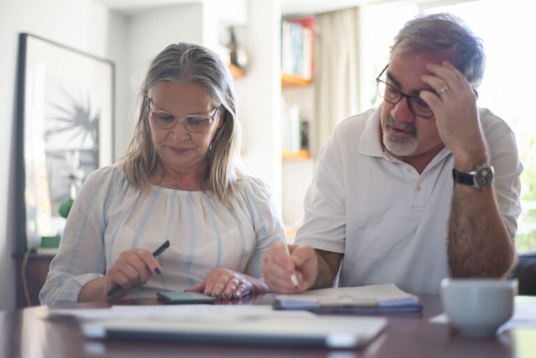 Older couple reviewing financial papers and making notes at a desk