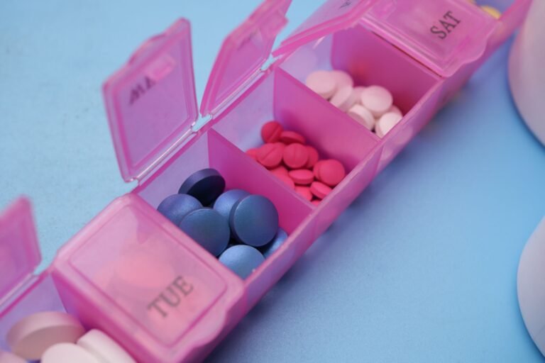 Weekly medication organizer with assorted tablets on a plain background