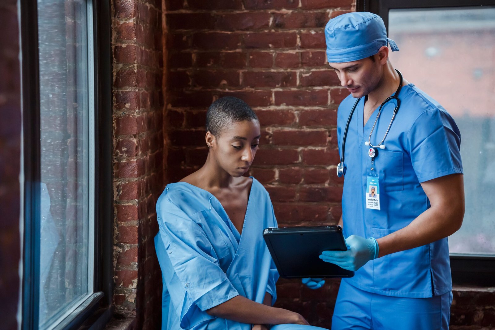 Healthcare professional discussing a document with a patient in a corridor.