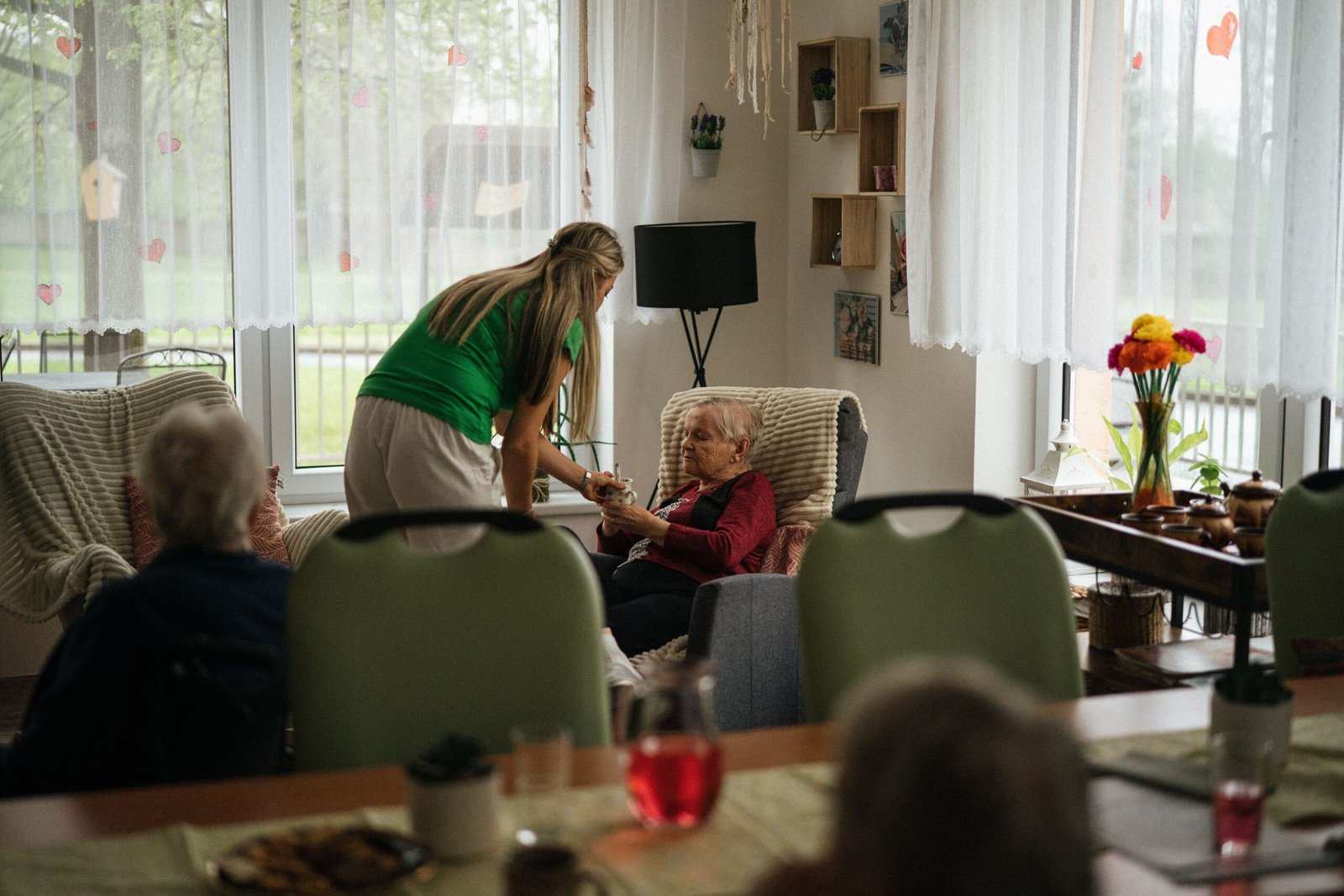 Caregiver sharing tea with older women in a care home