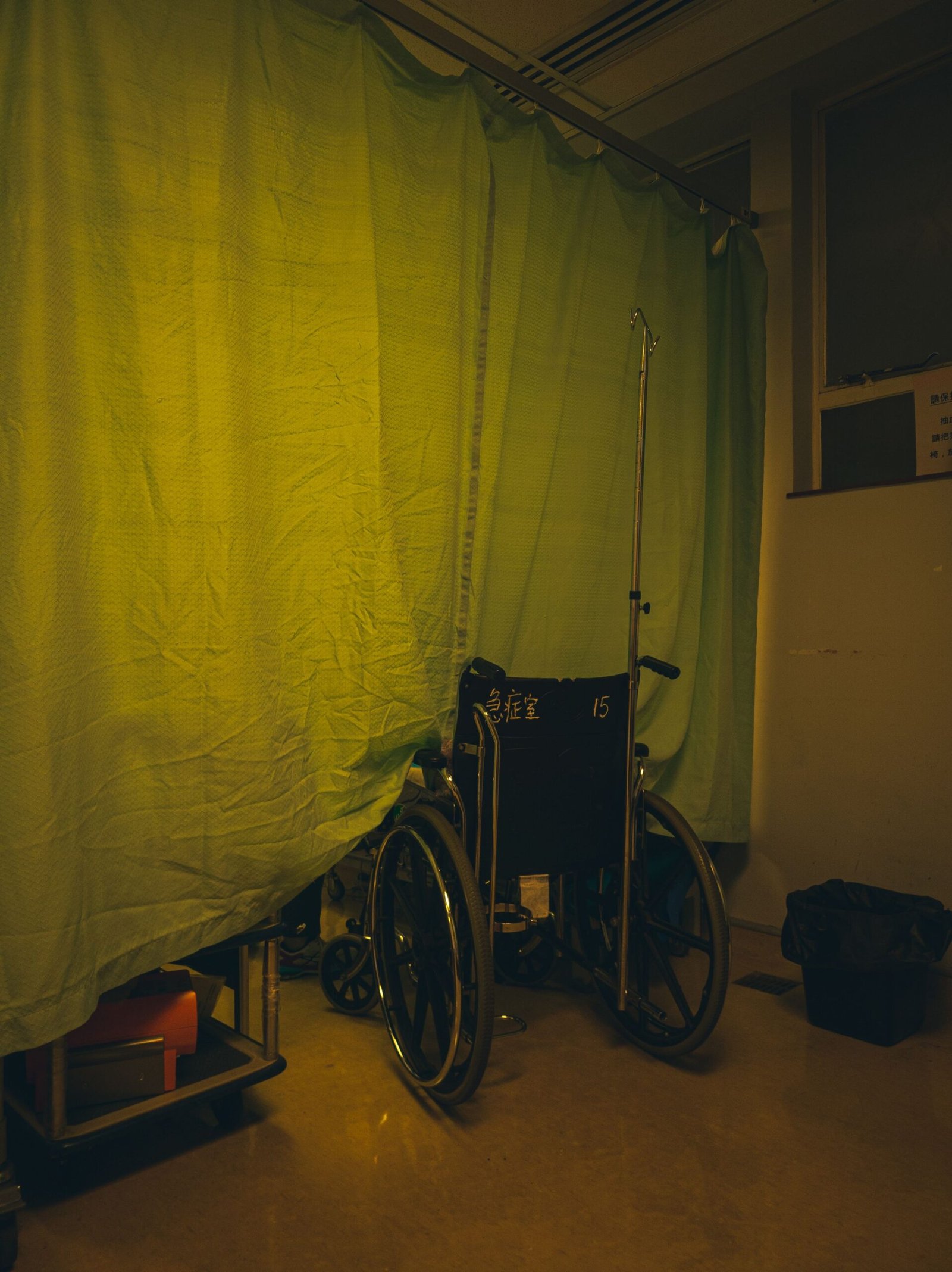 Empty wheelchair positioned beside a curtain in a quiet care room
