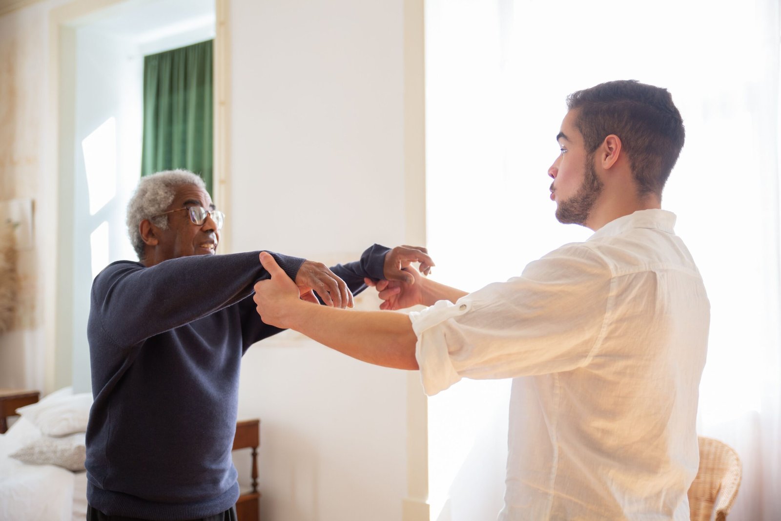 Older man talking and holding hands with a caregiver at home