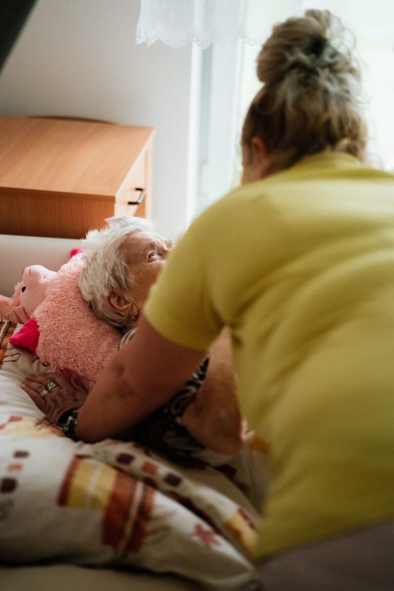 Nurse assisting an older woman resting in bed
