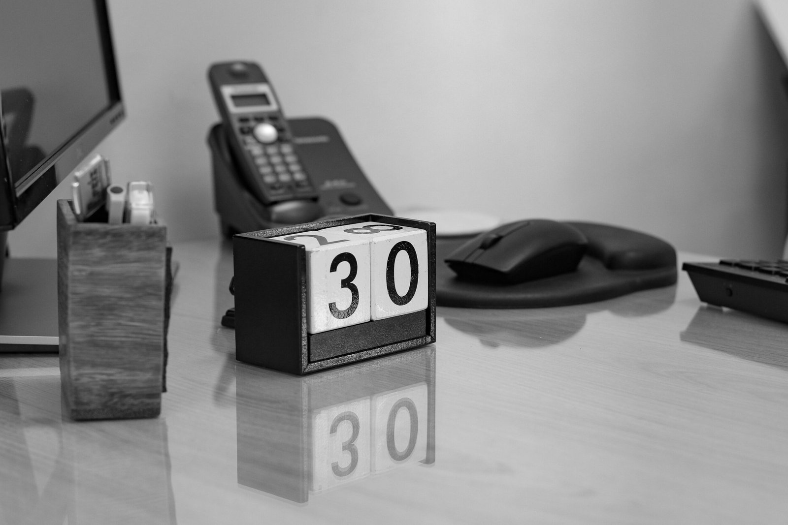 Desk calendar beside a phone, pencil cup, and keyboard.