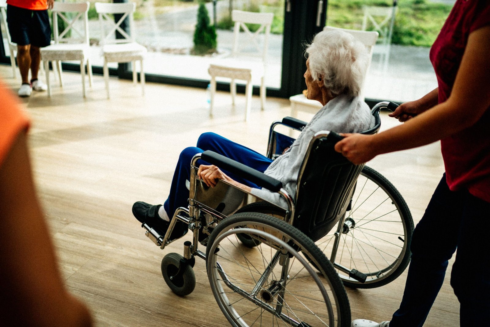 Caregiver assisting an older adult in a wheelchair in a nursing-home setting