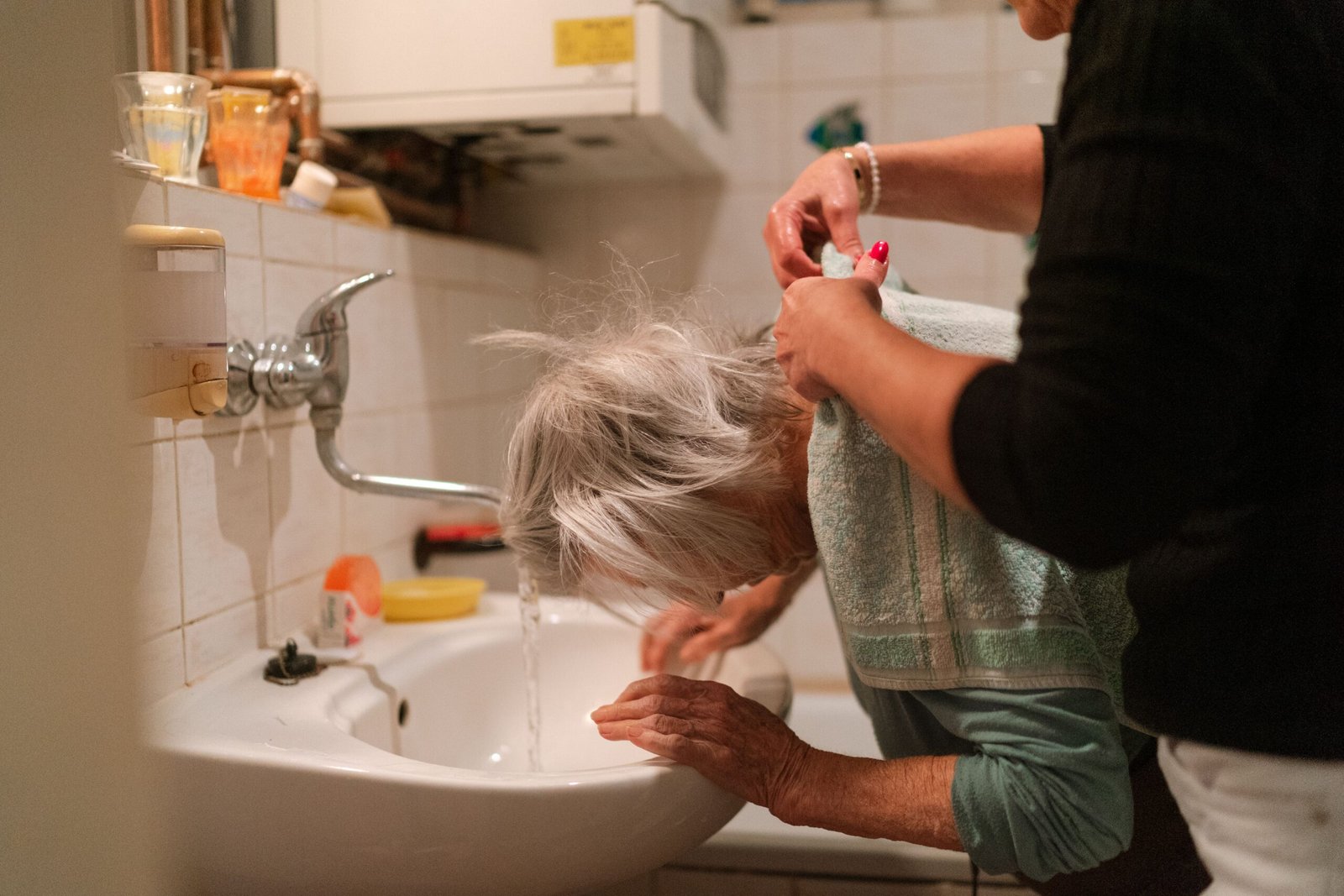 Caregiver assisting an older woman with personal care in a bathroom