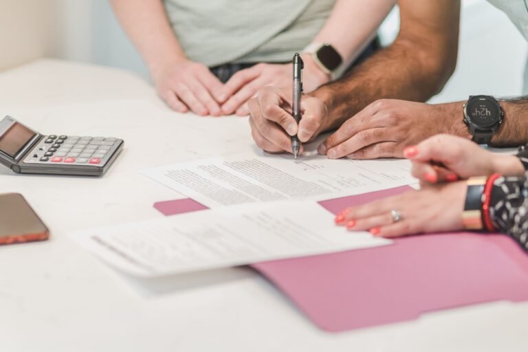 Person completing financial paperwork beside a calculator.