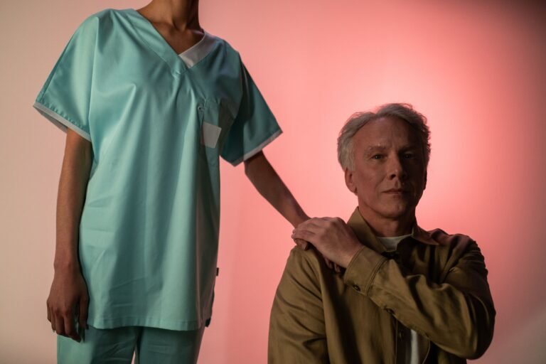 Nurse standing beside an older man and holding his hand