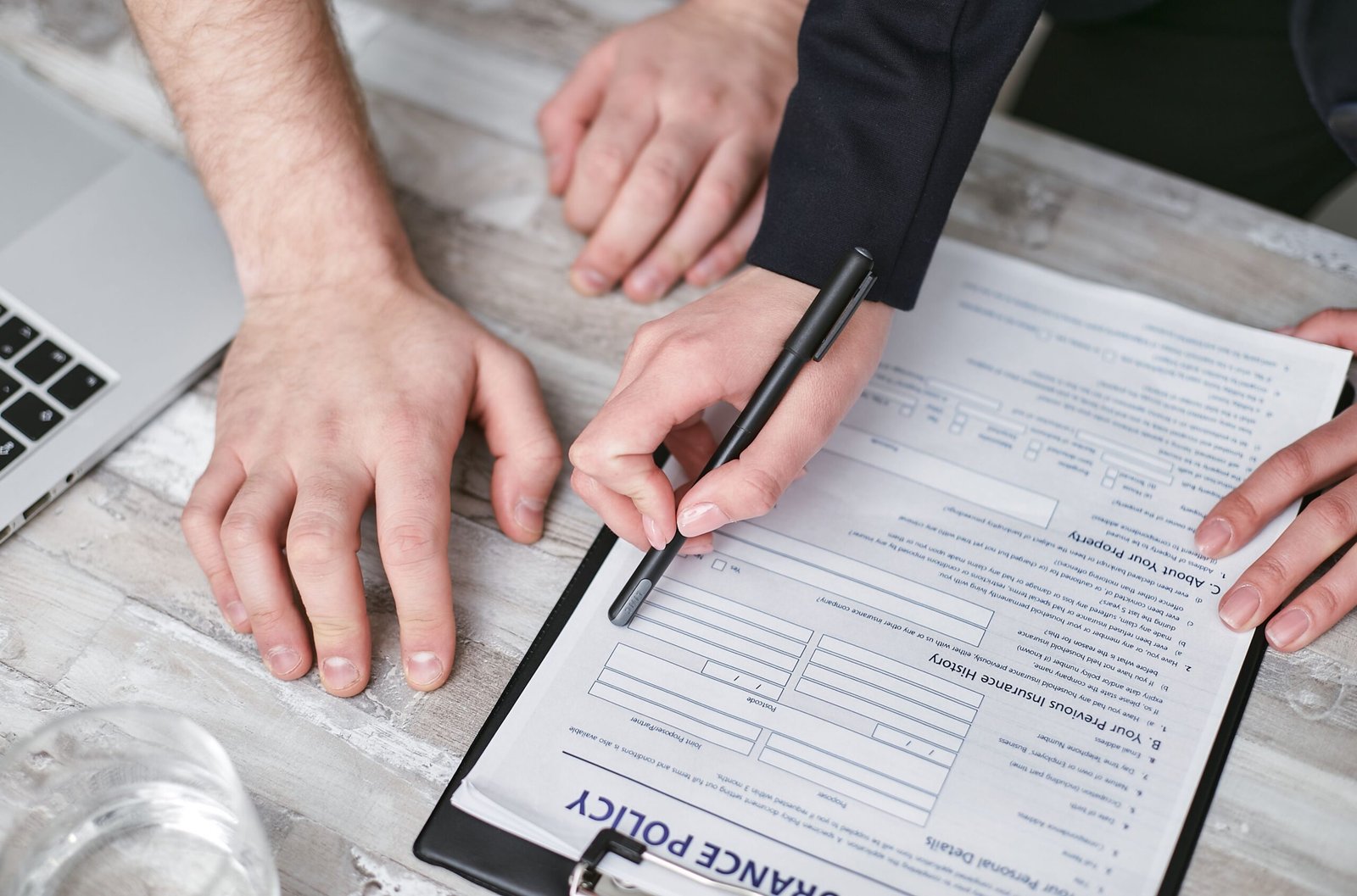 Hands reviewing and signing insurance policy documents at a desk.