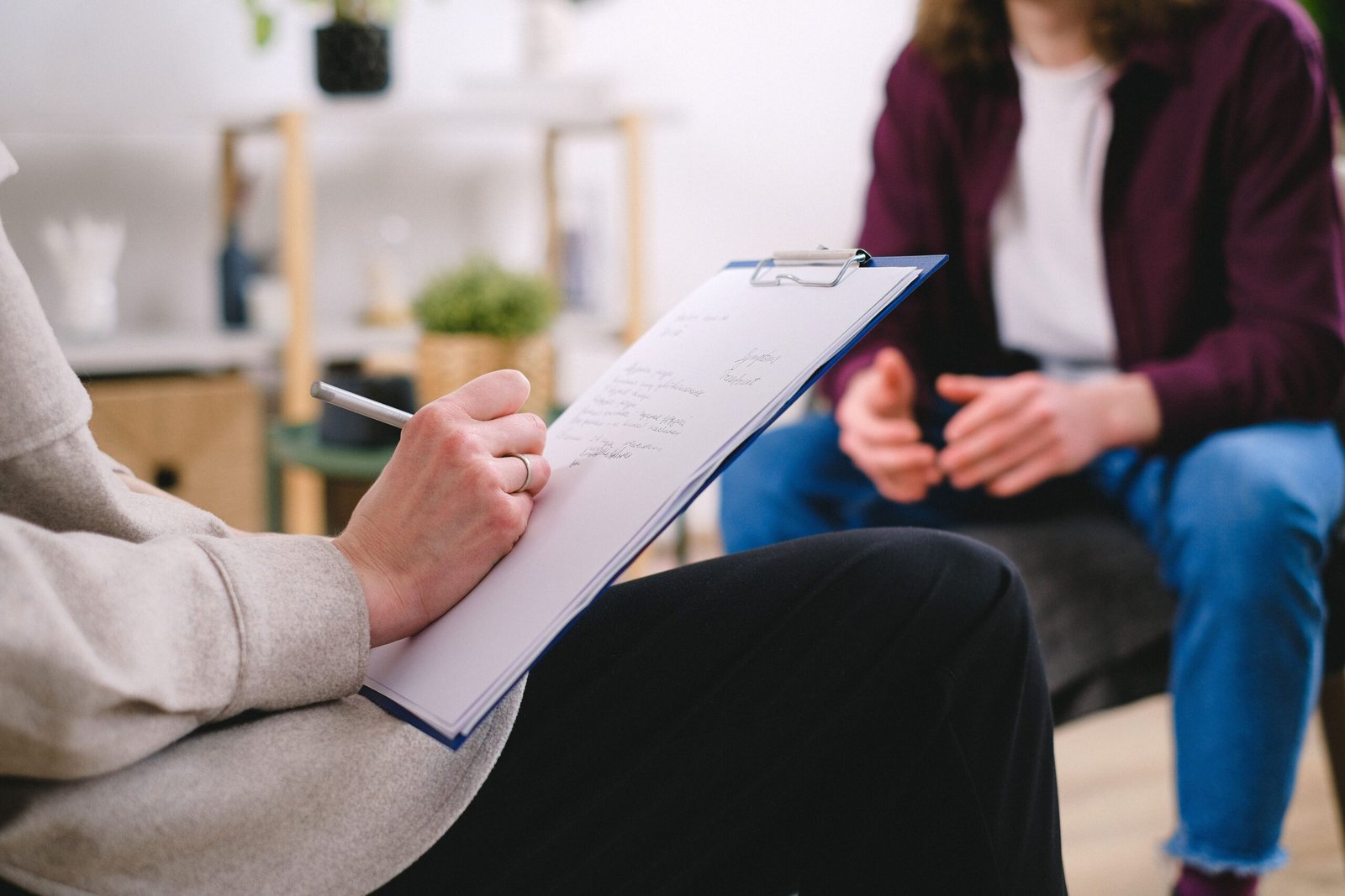 Therapist writing notes on a clipboard during a care discussion.