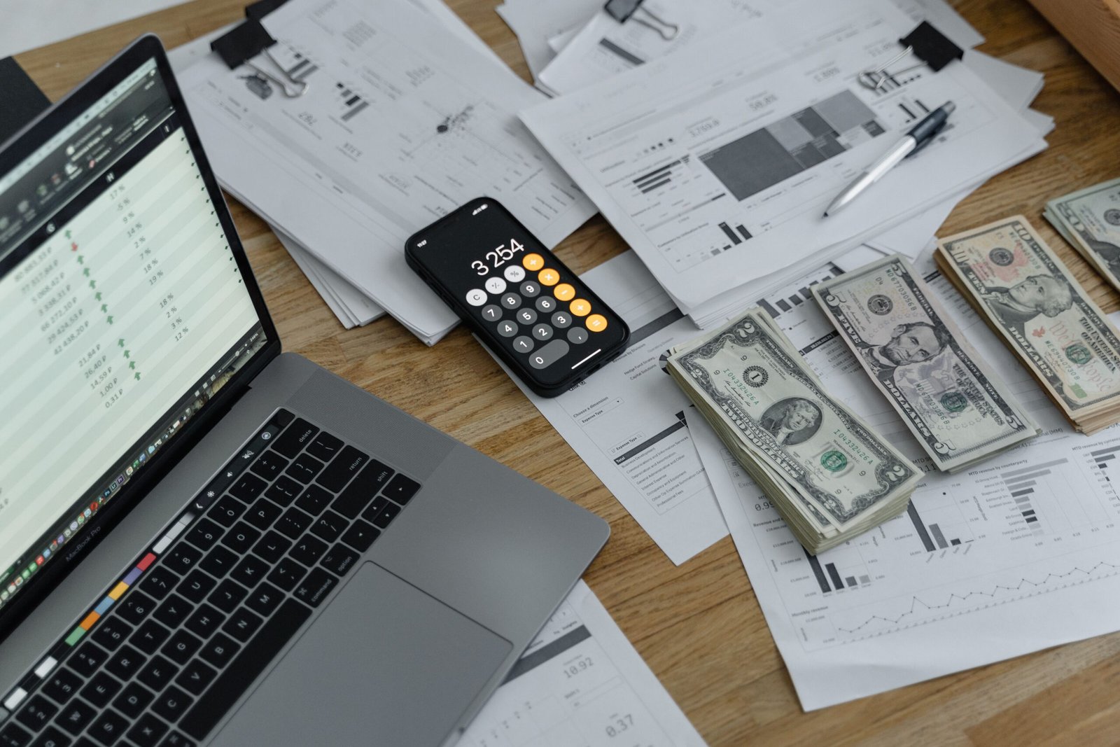 Banknotes, calculator, and documents arranged for reporting financial changes.