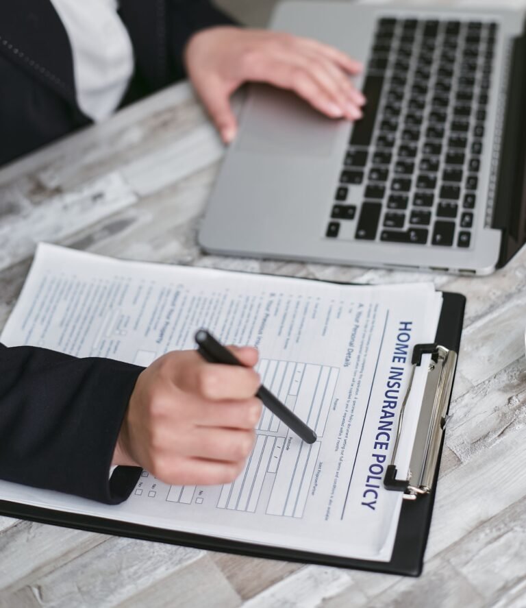 Person reviewing and signing an insurance policy document at a desk.