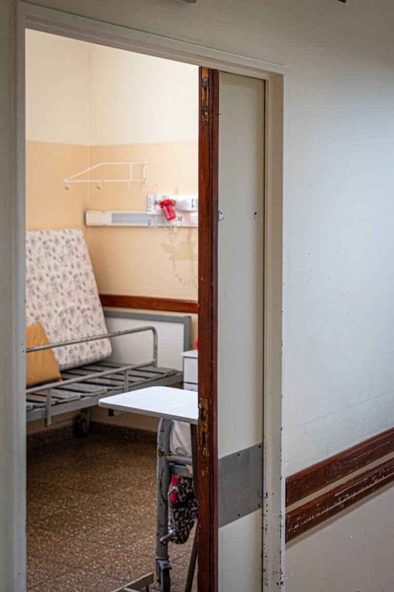 View into an empty healthcare room with a single bed and medical equipment.