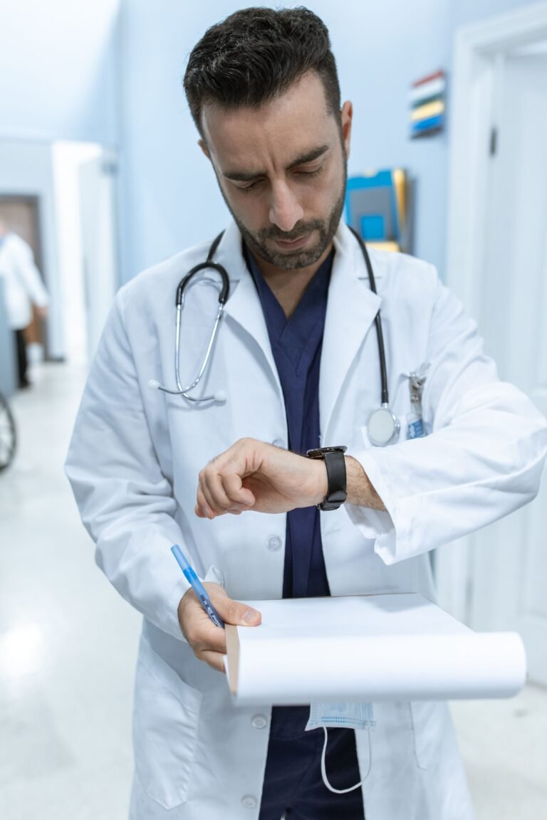 Doctor holding a clipboard and checking a watch in a healthcare corridor.