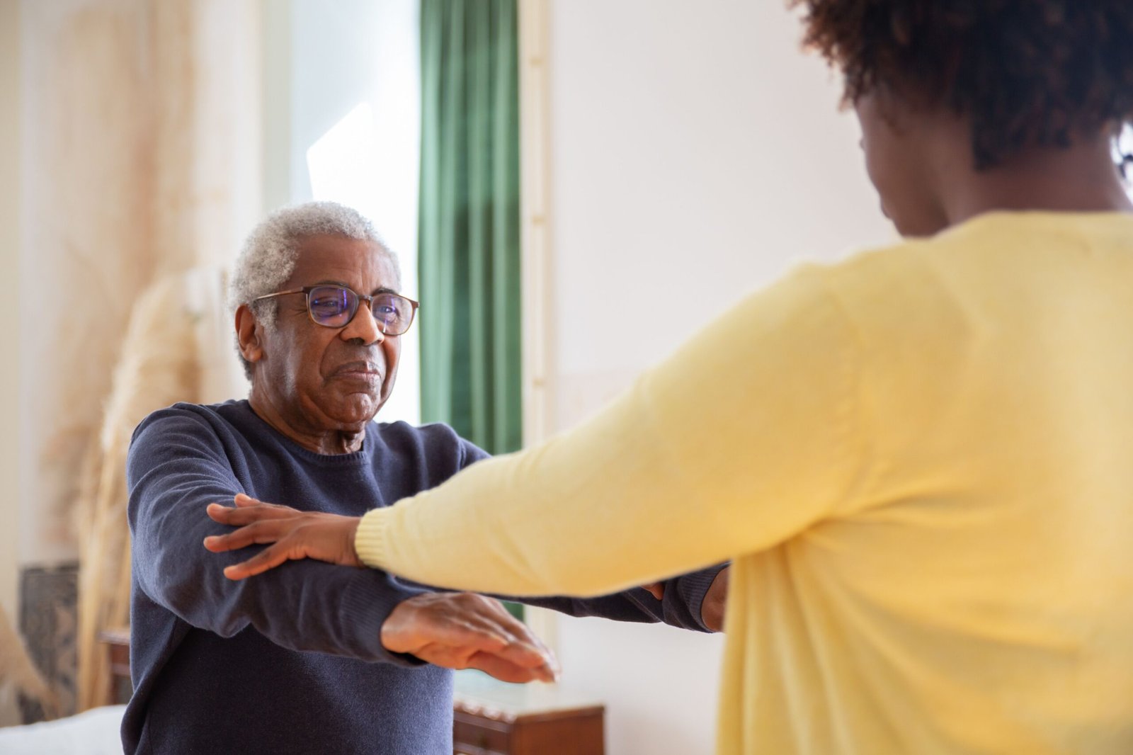 Caregiver helping an older man with gentle physical exercises