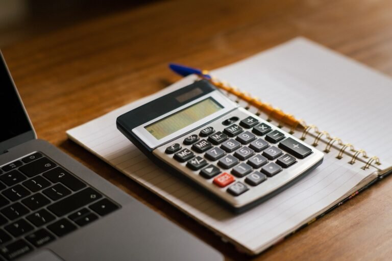Calculator and laptop arranged on a wooden desk for financial planning.