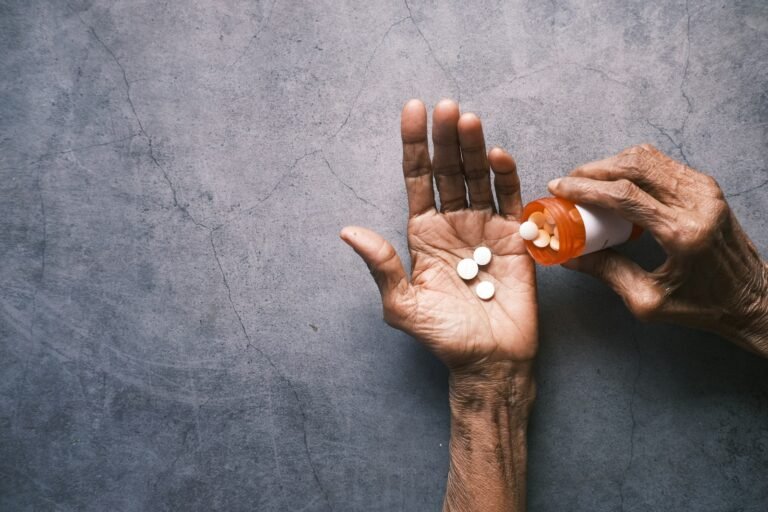 Older adult hand holding medications while reviewing a medication plan