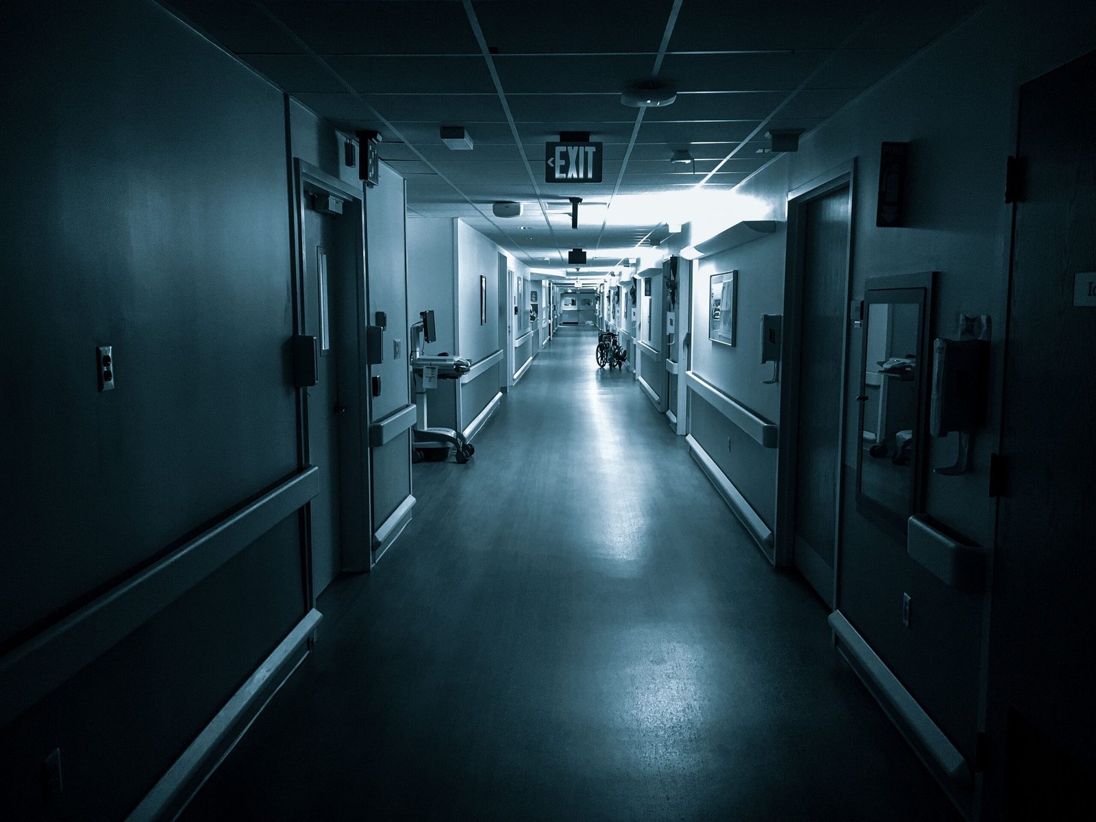 Quiet hospital corridor with a wheelchair visible in the distance.