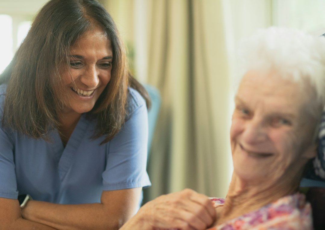 Nurse smiling with an older patient during bedside care