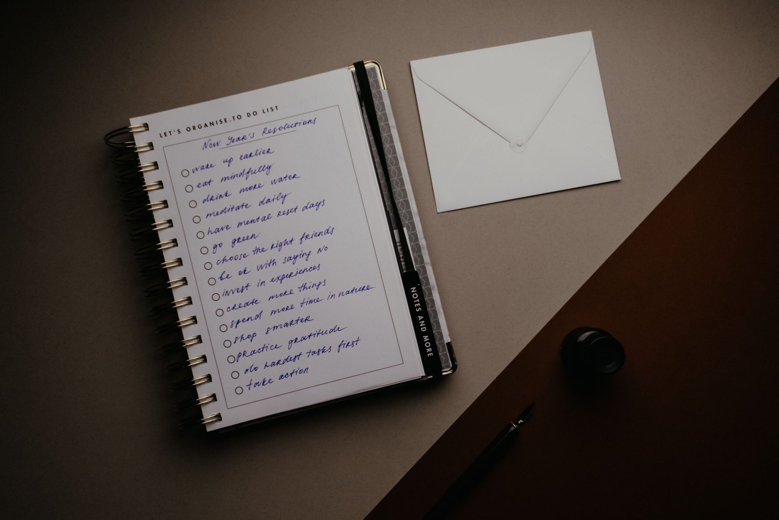 Notebook, checklist, and envelope arranged on a desk.