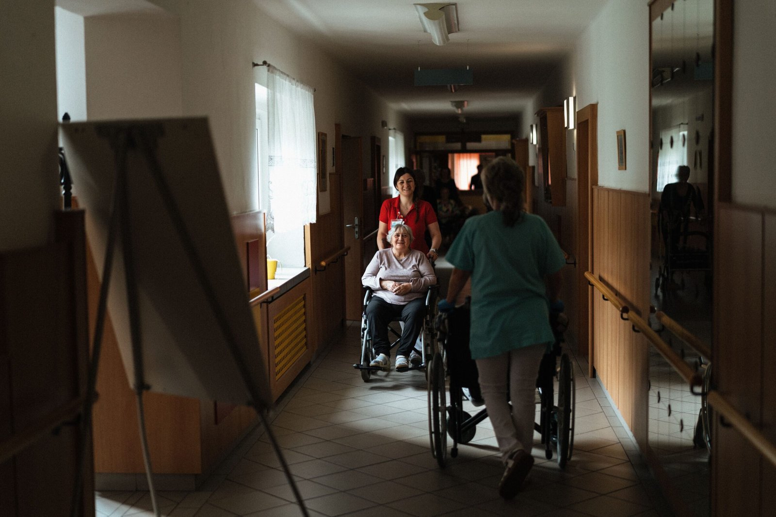 Caregiver assisting an older adult in a wheelchair at a nursing home