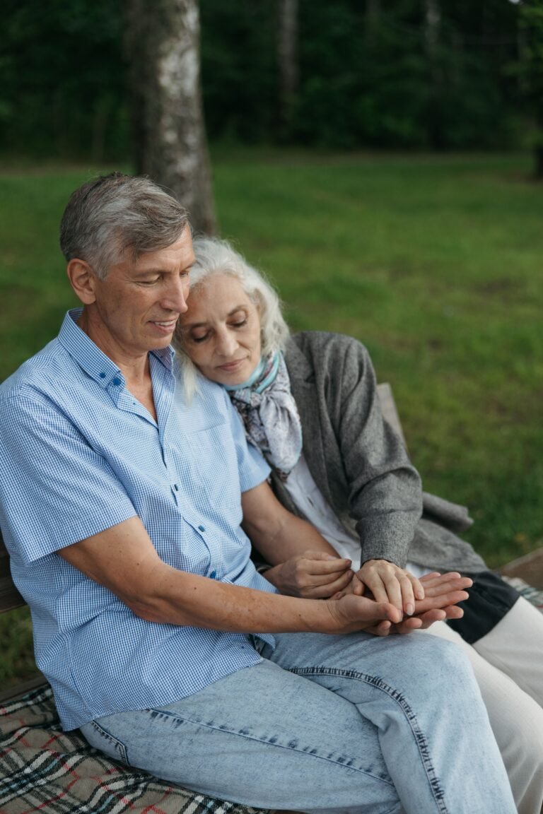 Older couple sitting close together on a park bench.