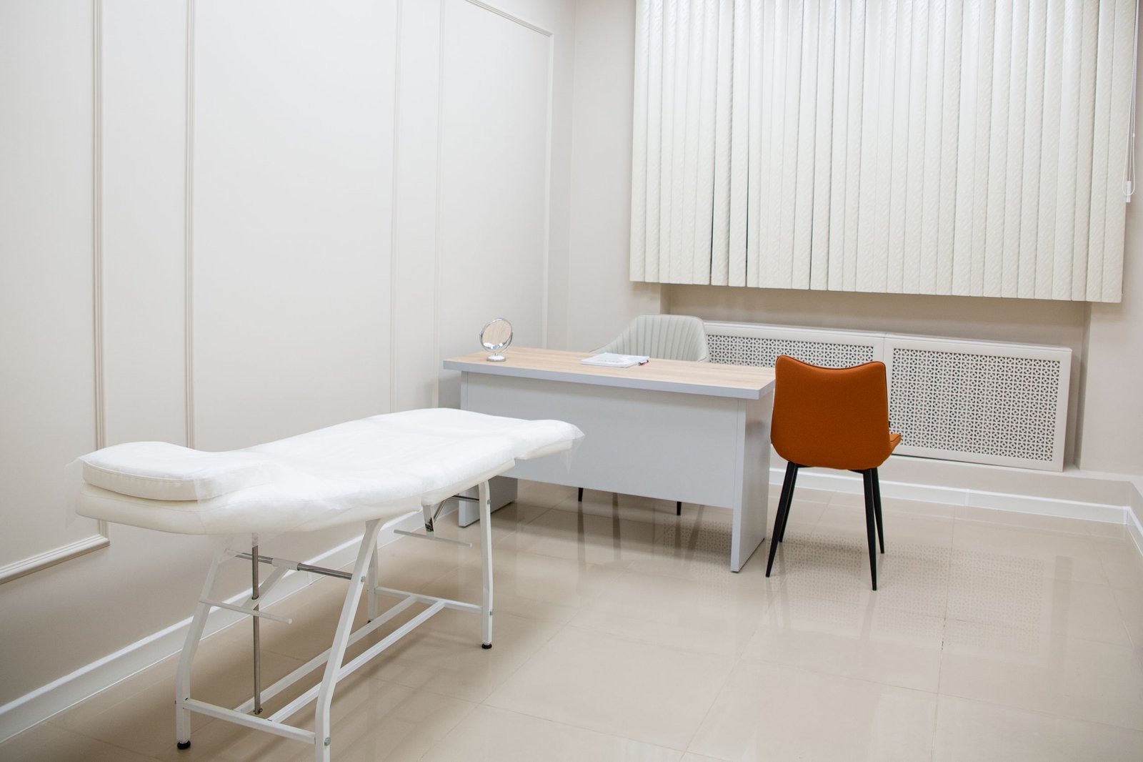 Empty medical examination room with a treatment table and chairs